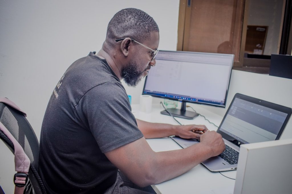 a-man-sitting-at-a-desk-using-a-laptop-computer-wjt7o8wkreq